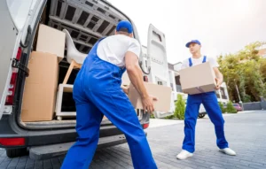 Mitarbeiter von Seniorenumzüge laden Umzugskartons aus einem weißen Umzugswagen aus. Ein- und Auspackservice